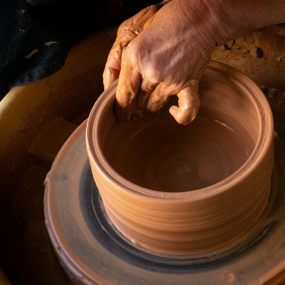 Persona che tiene un vaso di terracotta rotondo