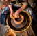 person in blue denim jeans making clay pot
