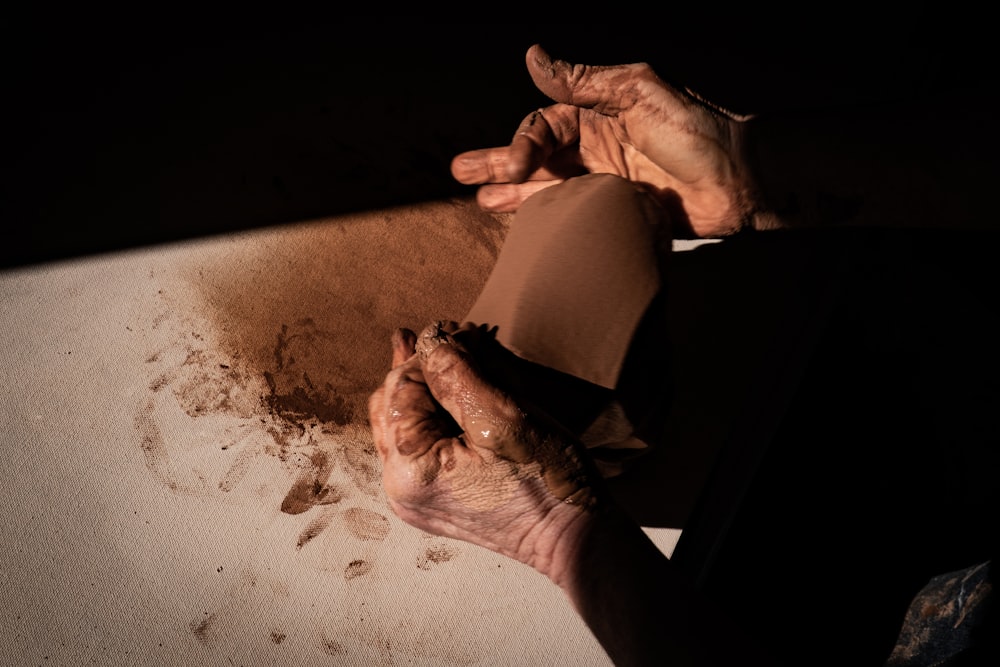 person holding white textile on gray sand