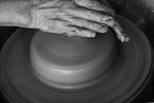 Hands gently shaping clay on a potter’s wheel, captured in soft natural light emphasizing form.