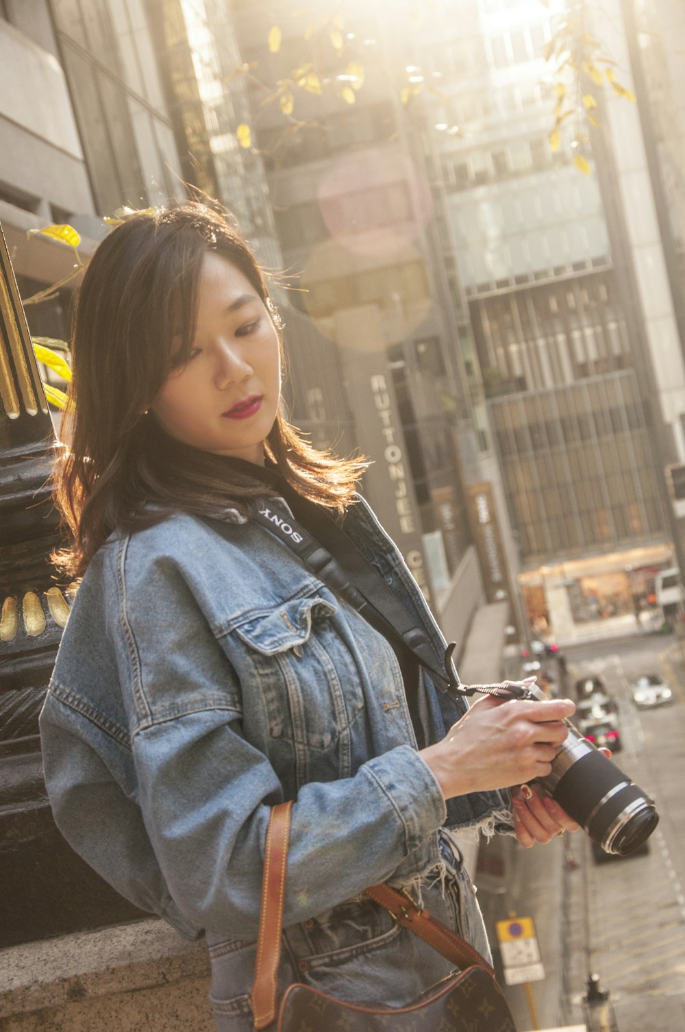 woman in blue denim jacket holding black dslr camera