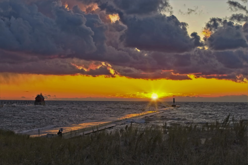 body of water under cloudy sky during sunset