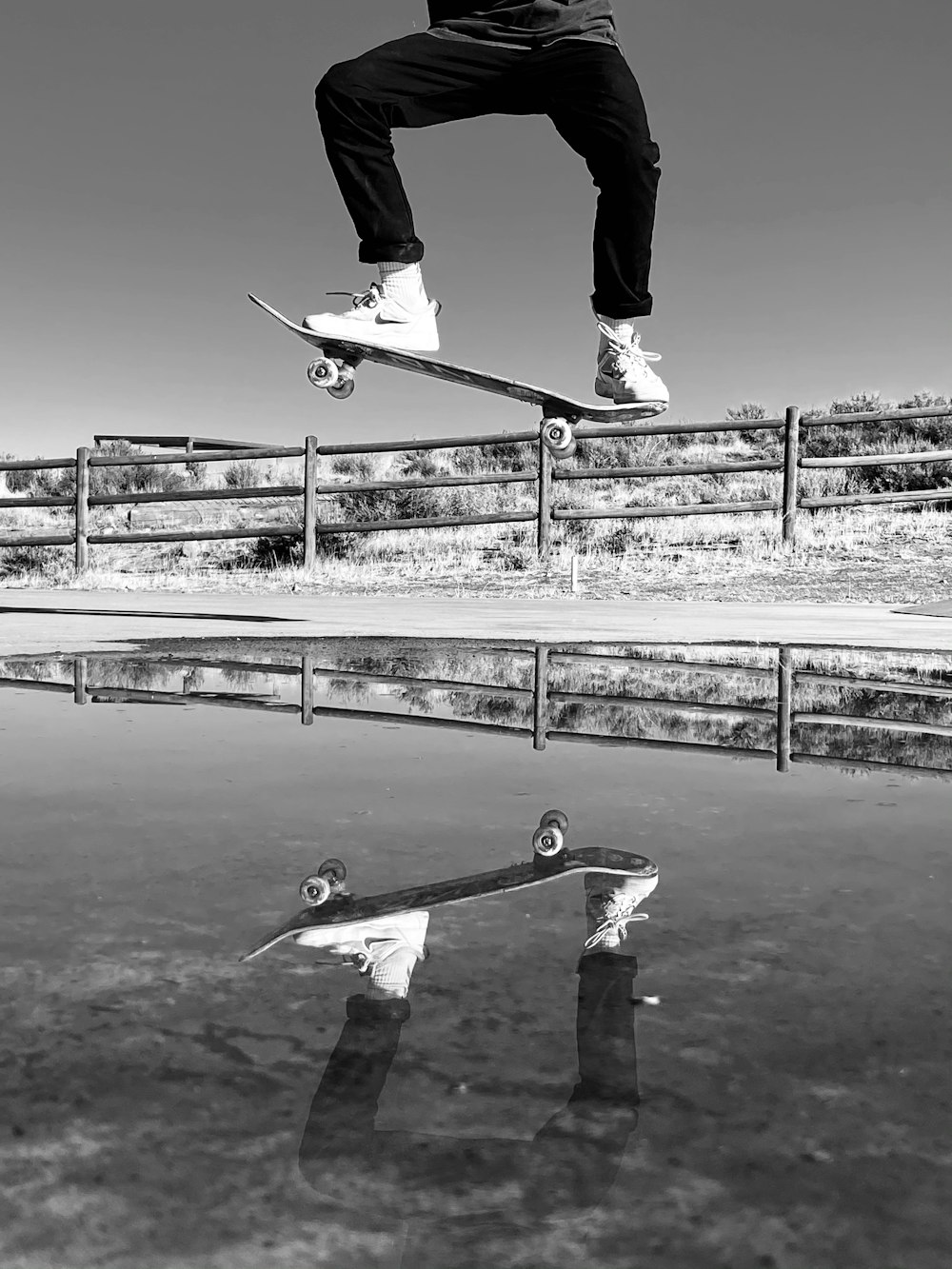 man in black pants and black jacket riding skateboard in grayscale photography