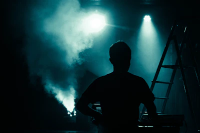 A silhouette of an actor rehearsing on a dimly lit stage.