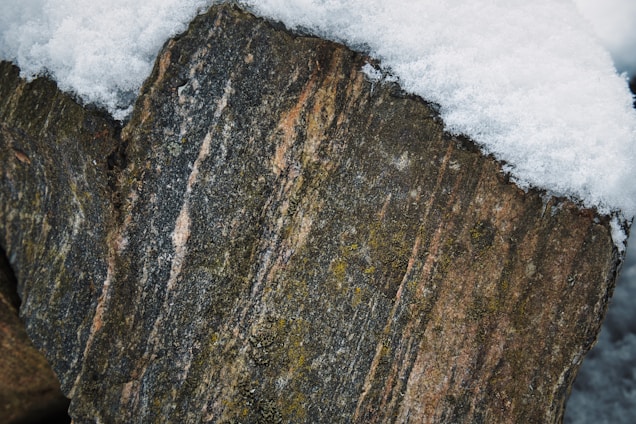 A close-up of soft, breathable ski base layer fabric in cool tones, draped over snowy mountain rocks.