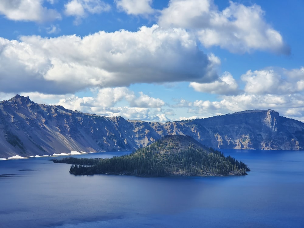 blue lake near green mountain under white clouds and blue sky during daytime