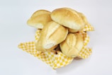 Freshly baked bread rolls arranged on a linen cloth with a small dish of butter.