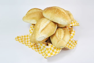 Warm, soft bread rolls fresh out of the oven stacked neatly in a red and white bakery basket.