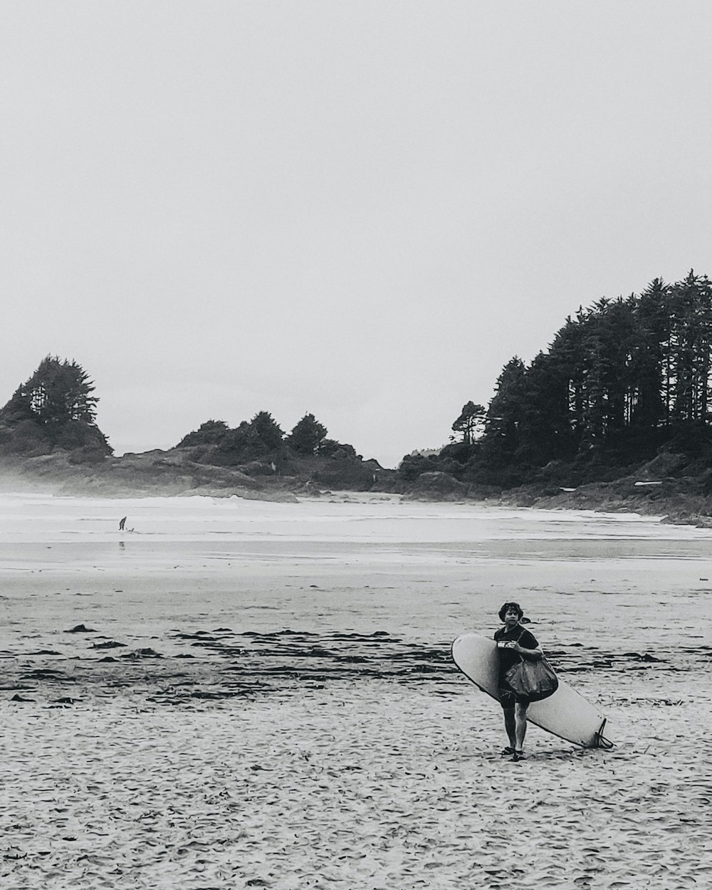 person in black shirt carrying white surfboard walking on beach during daytime