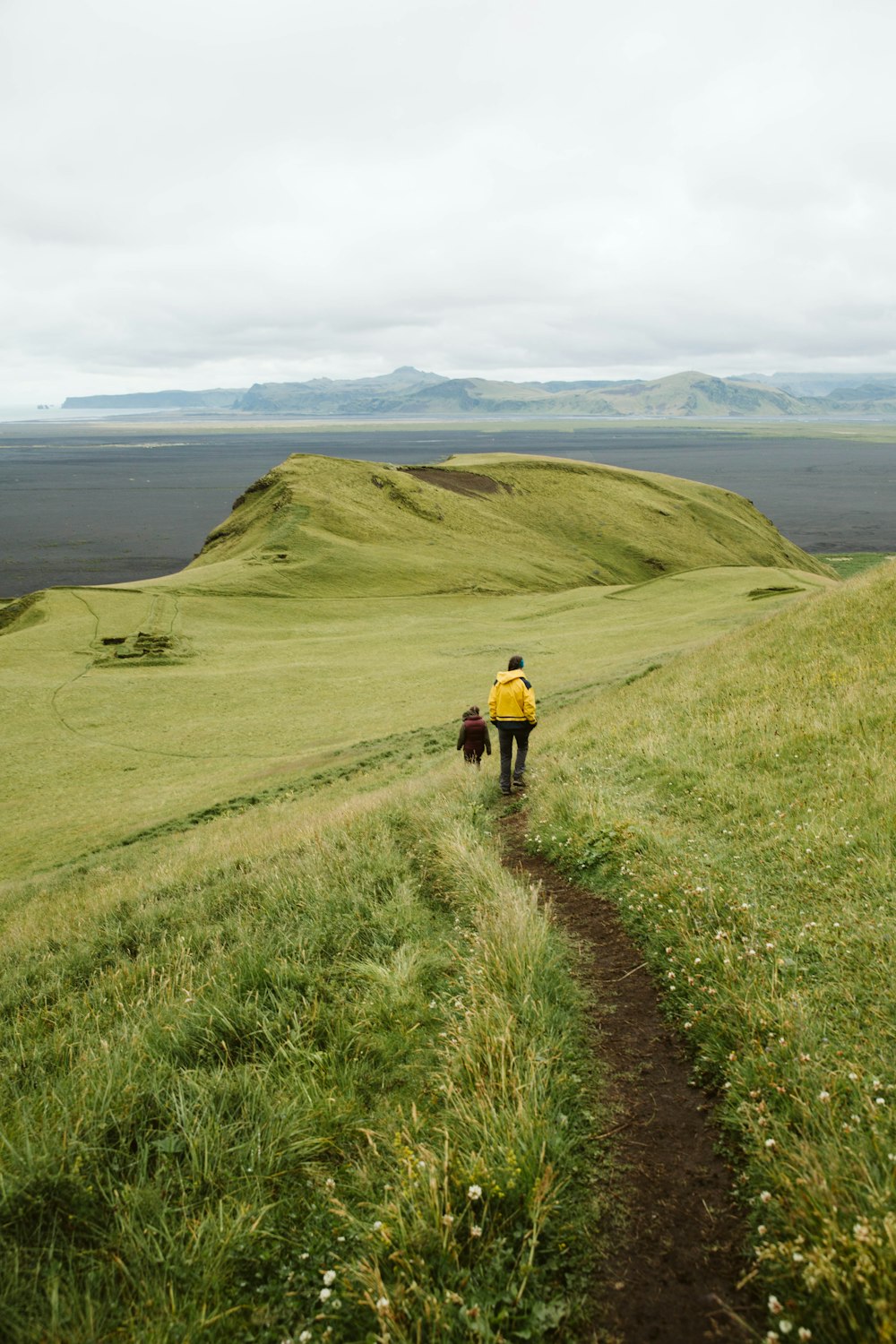 man in red jacket walking on green grass field during daytime