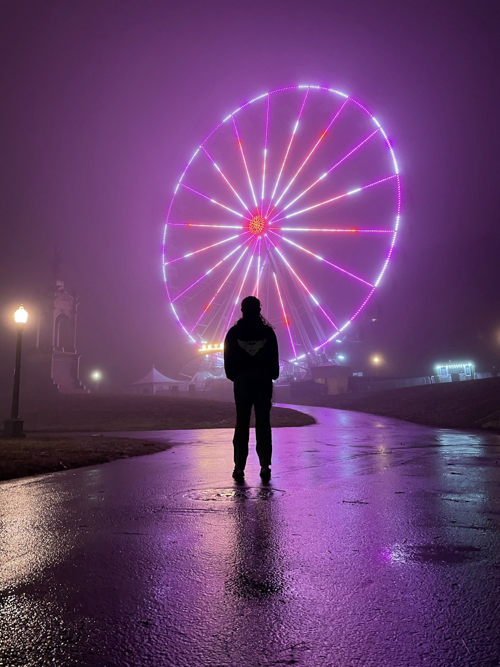 persona in piedi sulla spiaggia con luci viola