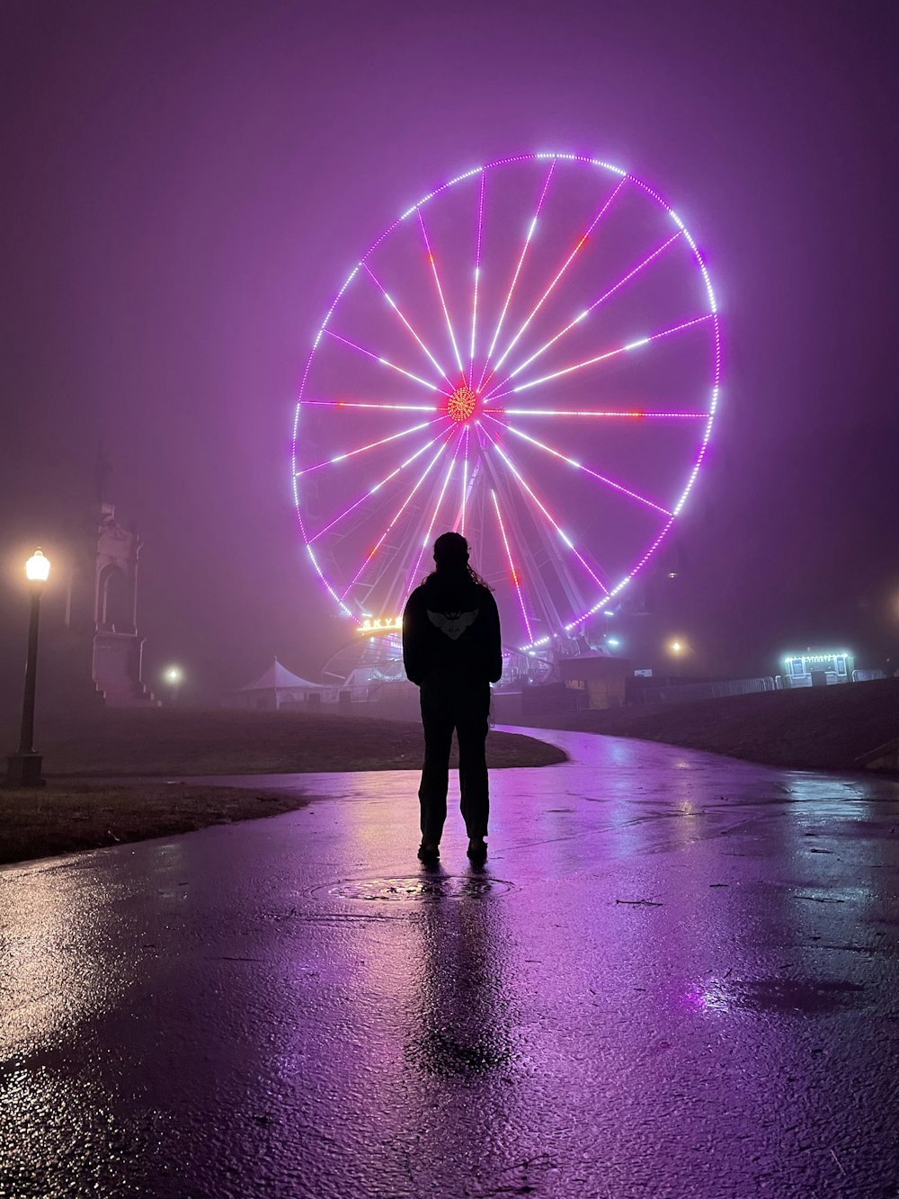 persona in piedi sulla spiaggia con luci viola