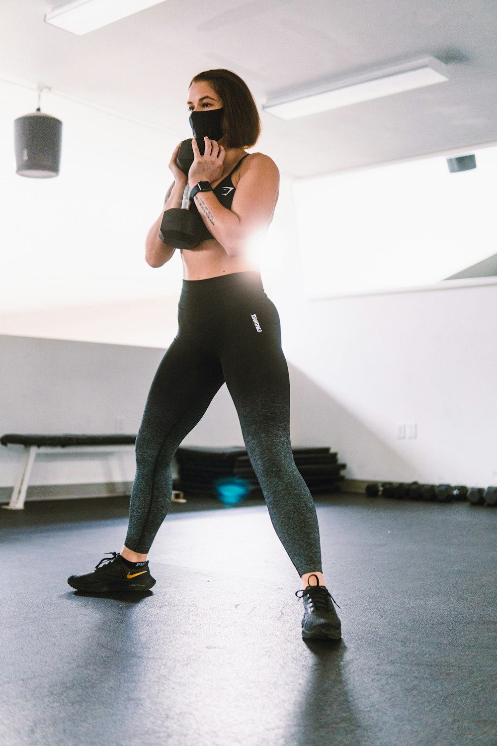 woman in black tank top and blue leggings doing yoga