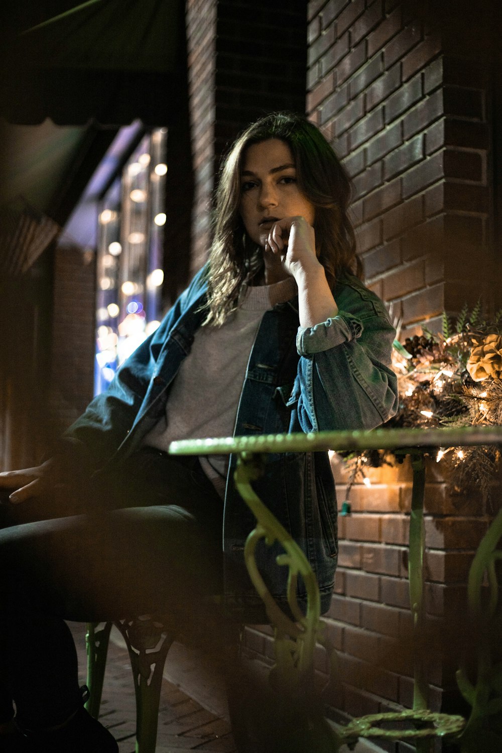 woman in green long sleeve shirt and blue denim jeans sitting on green metal bar