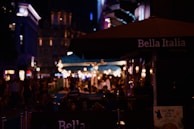 Evening street scene with warm lights and lively outdoor dining in Vieste’s old town.