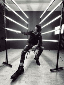grayscale photo of woman in long sleeve shirt and pants sitting on chair
