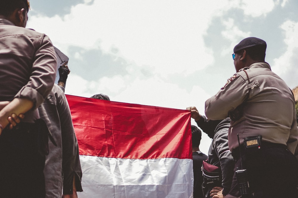 man in black jacket holding white and red flag