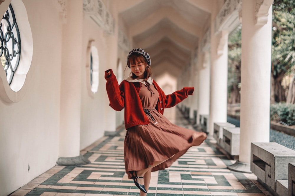 girl in red coat standing on white and black stripe floor