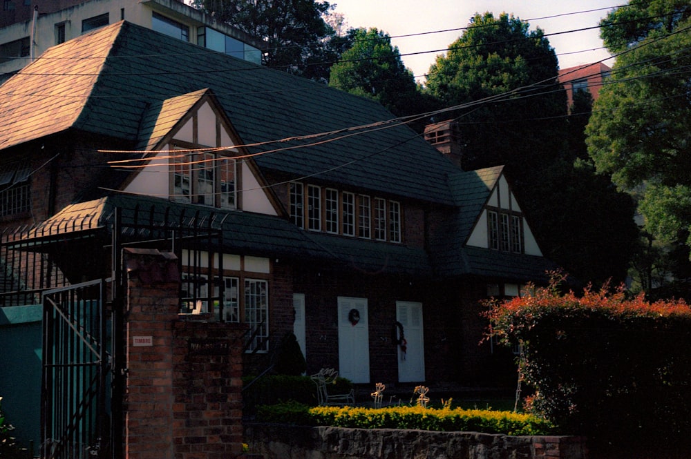 brown brick house with yellow flowers and green plants