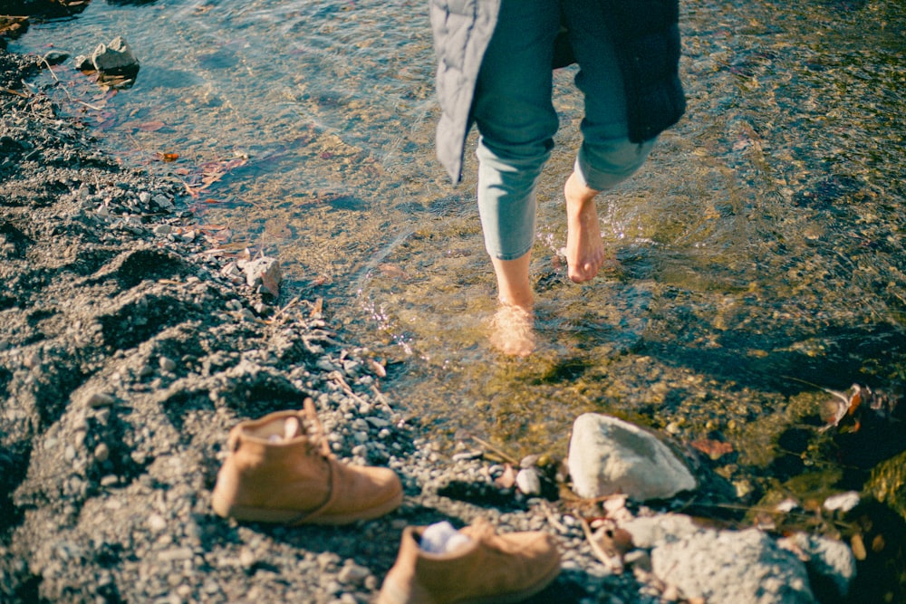 person in black pants standing on rocky shore during daytime