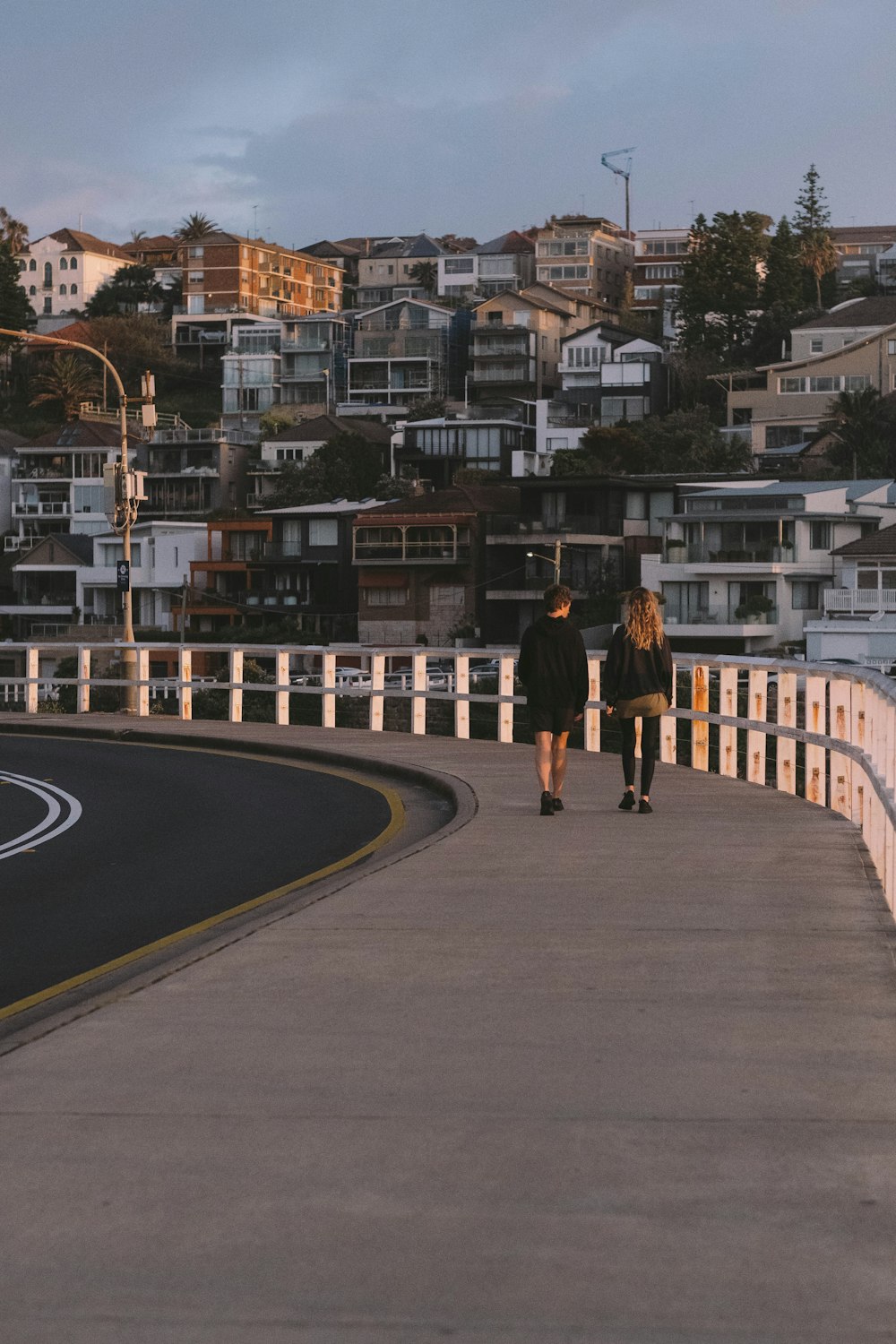 man in black jacket and black pants walking on gray asphalt road during daytime