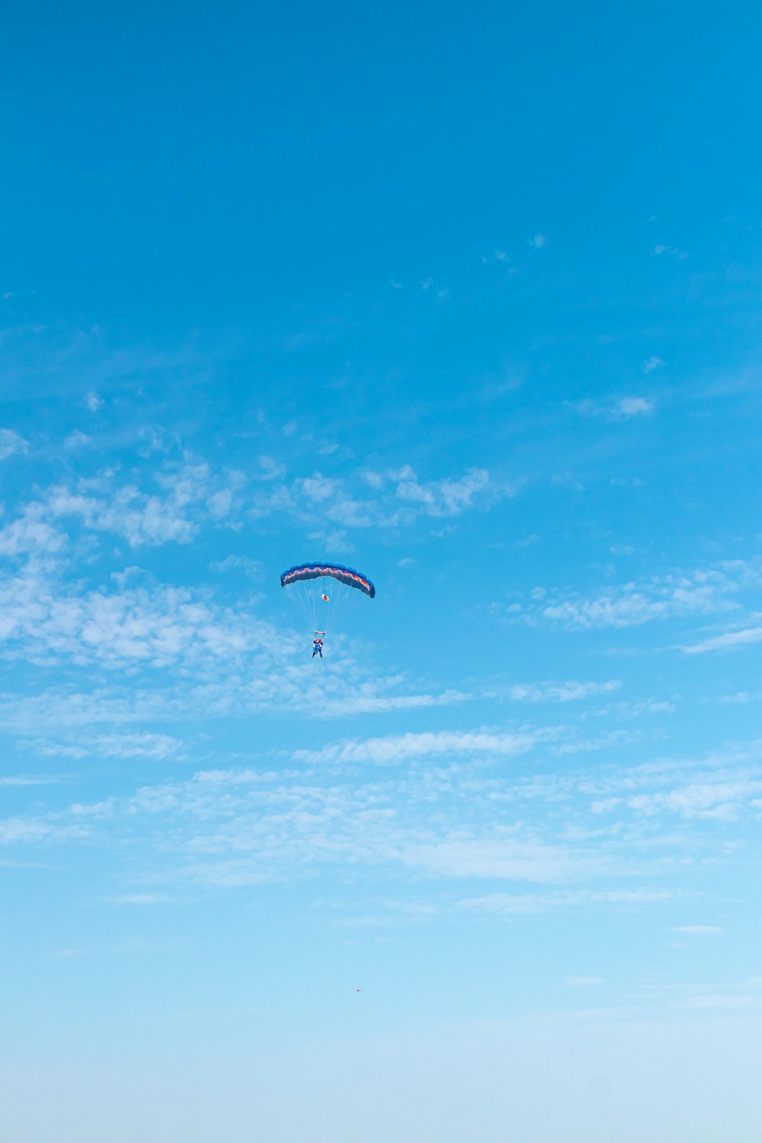 person in parachute under blue sky during daytime