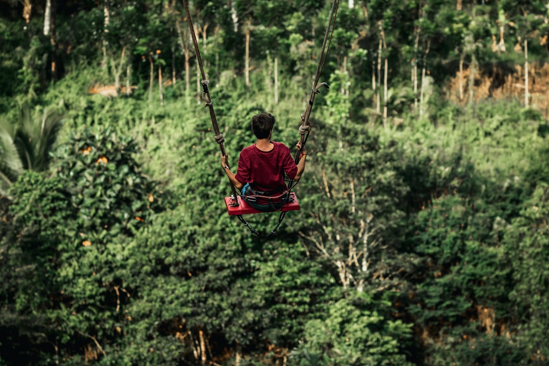 girl in red jacket riding on swing during daytime