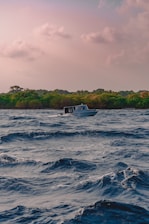 A rugged fishing boat cutting through choppy ocean waves at dawn.