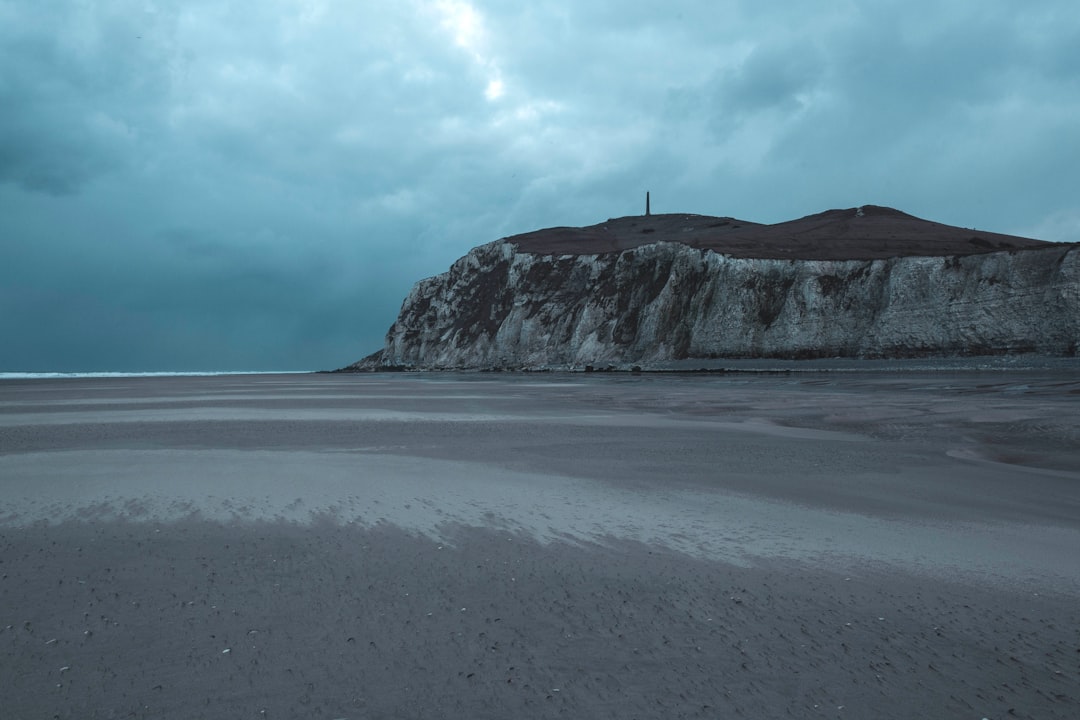 person standing on seashore near mountain during daytime