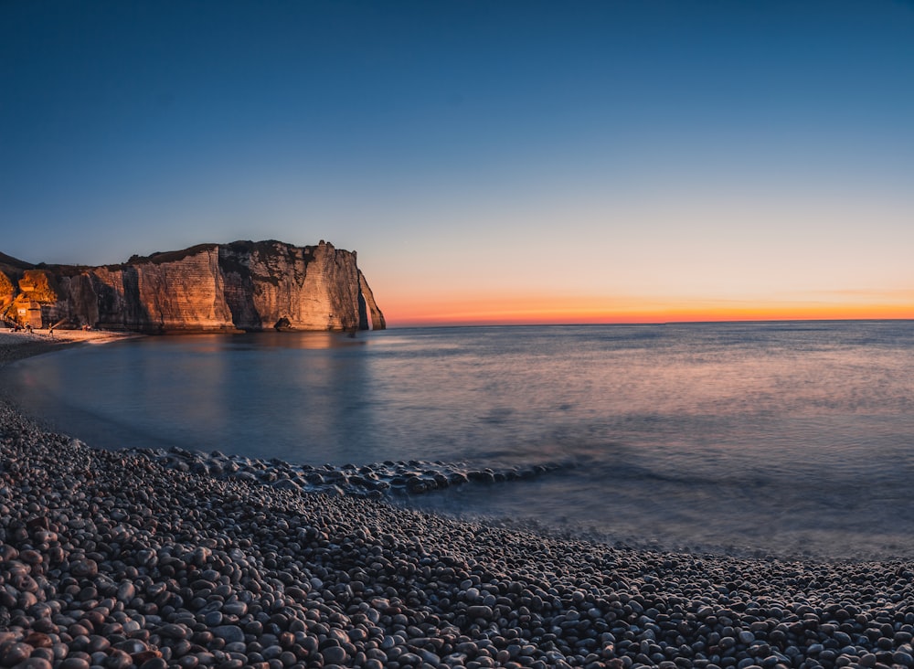 Montaña rocosa marrón junto al cuerpo de agua durante el día