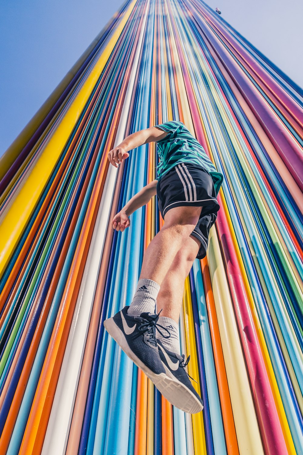 man in black shorts and black and white nike sneakers jumping on multi colored hammock during