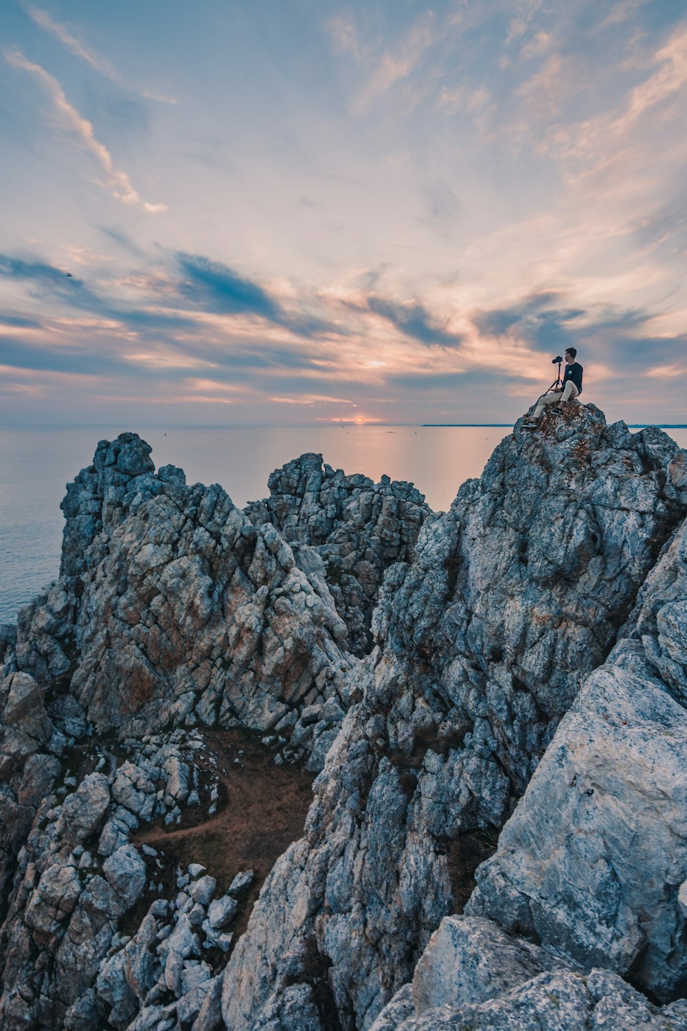 person standing on rock formation near body of water during daytime