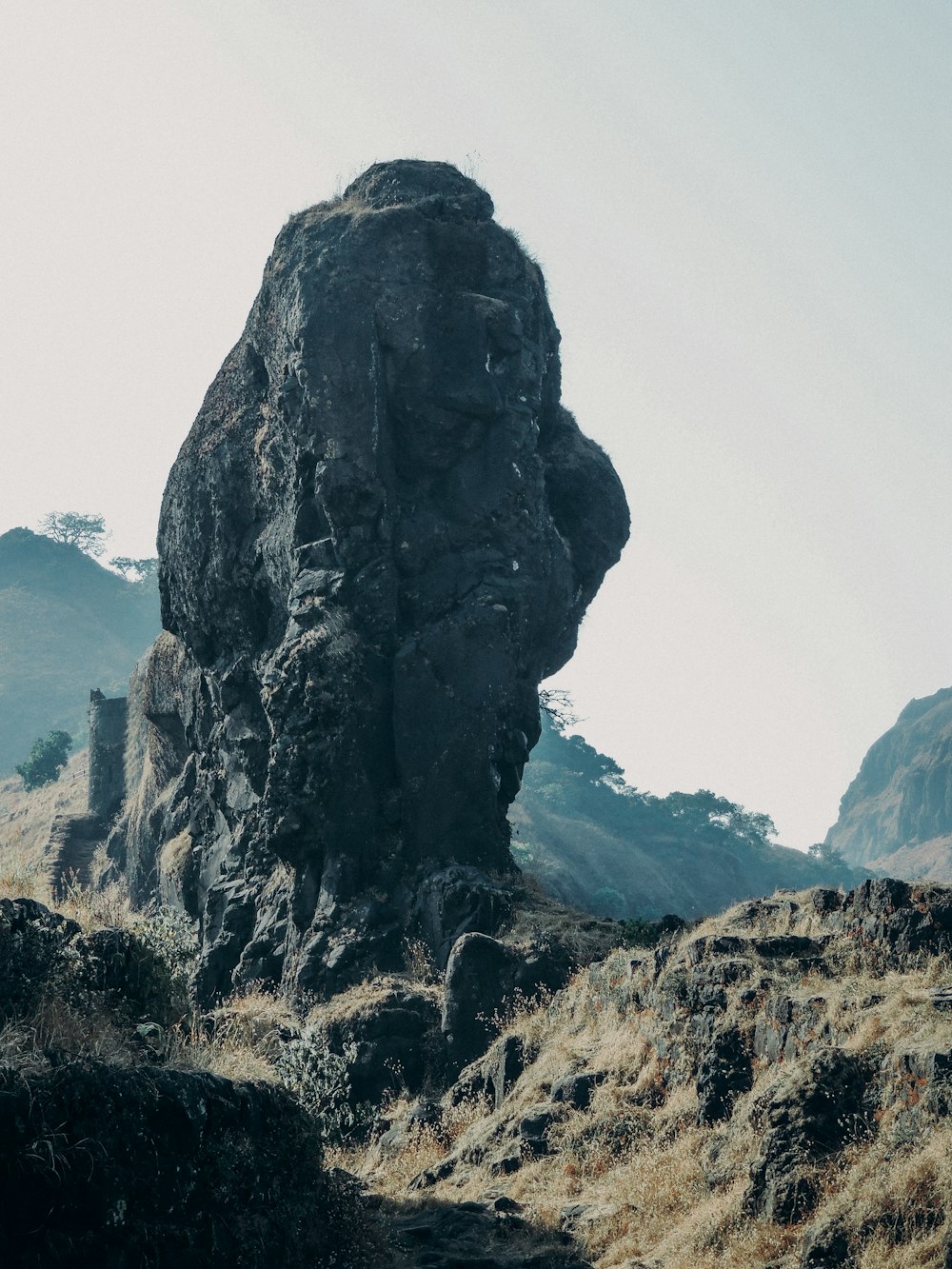 black rock formation on green grass field during daytime