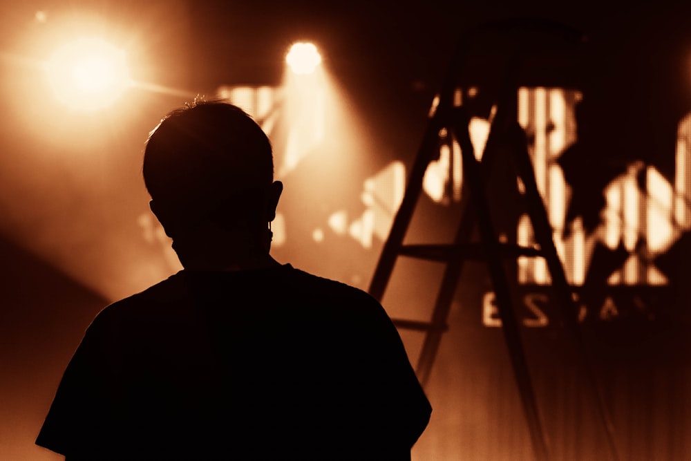 silhouette d’homme debout devant les lumières de la scène