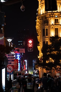 Workers installing illuminated signage on a busy city street.