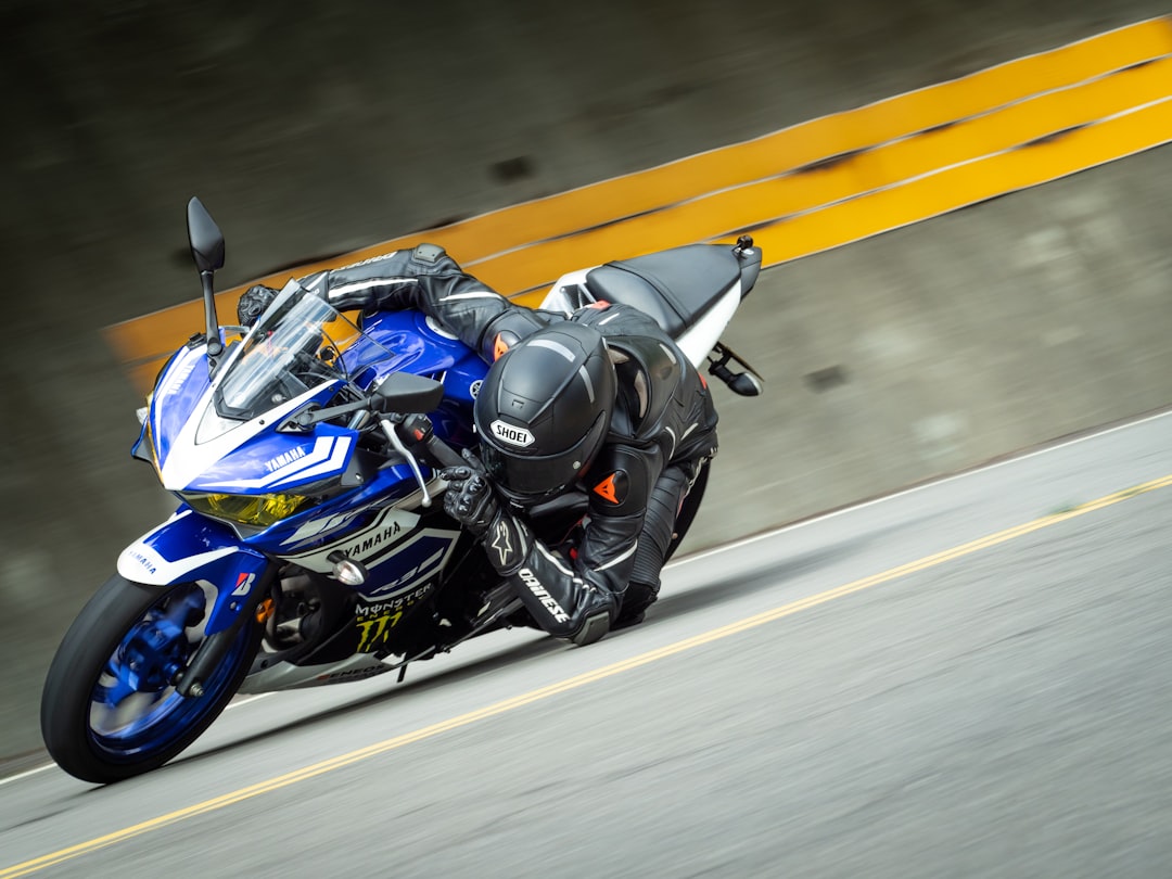 man in black and blue motorcycle suit riding blue and white sports bike