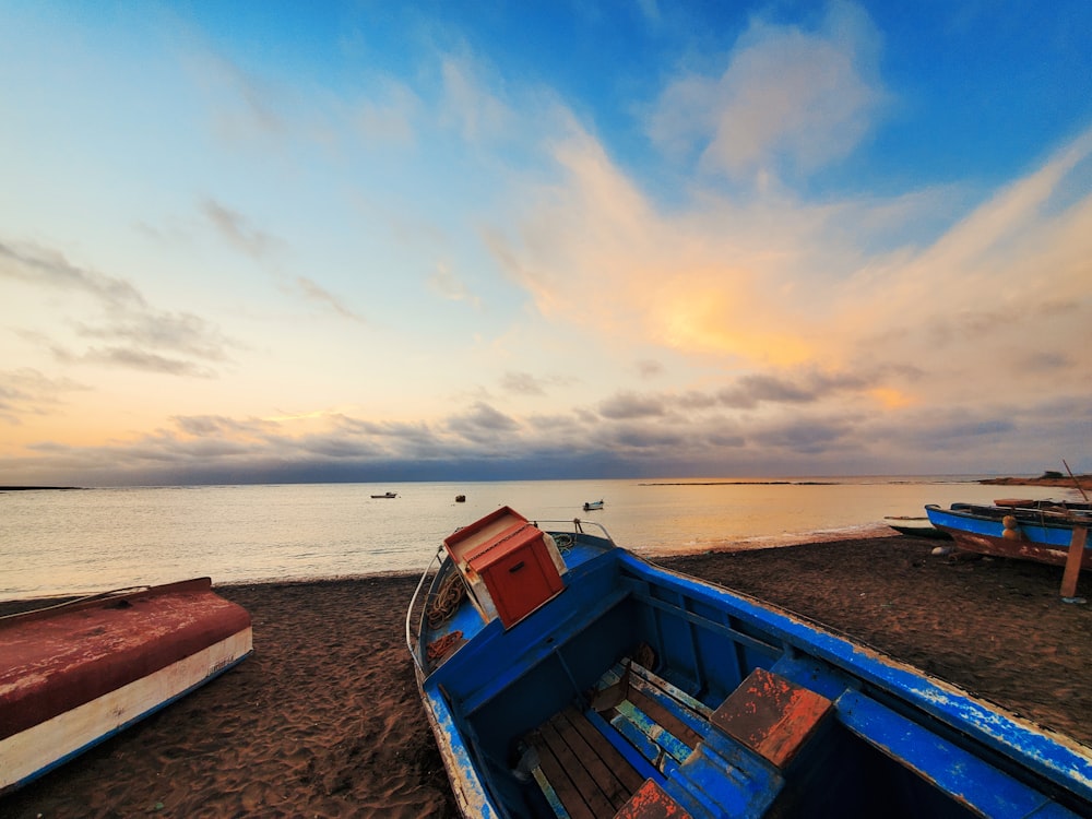 blue and red boat on beach during daytime