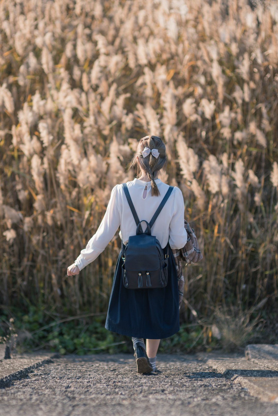 woman in white long sleeve shirt and blue skirt standing on brown grass field during daytime