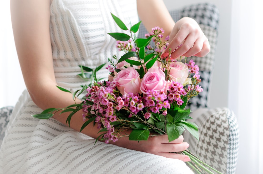 woman in white dress holding pink roses