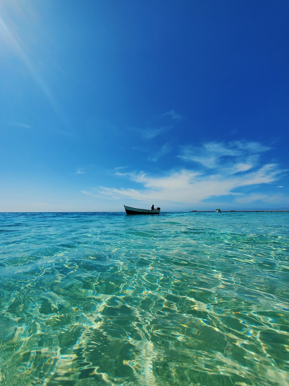 black boat on sea under blue sky during daytime