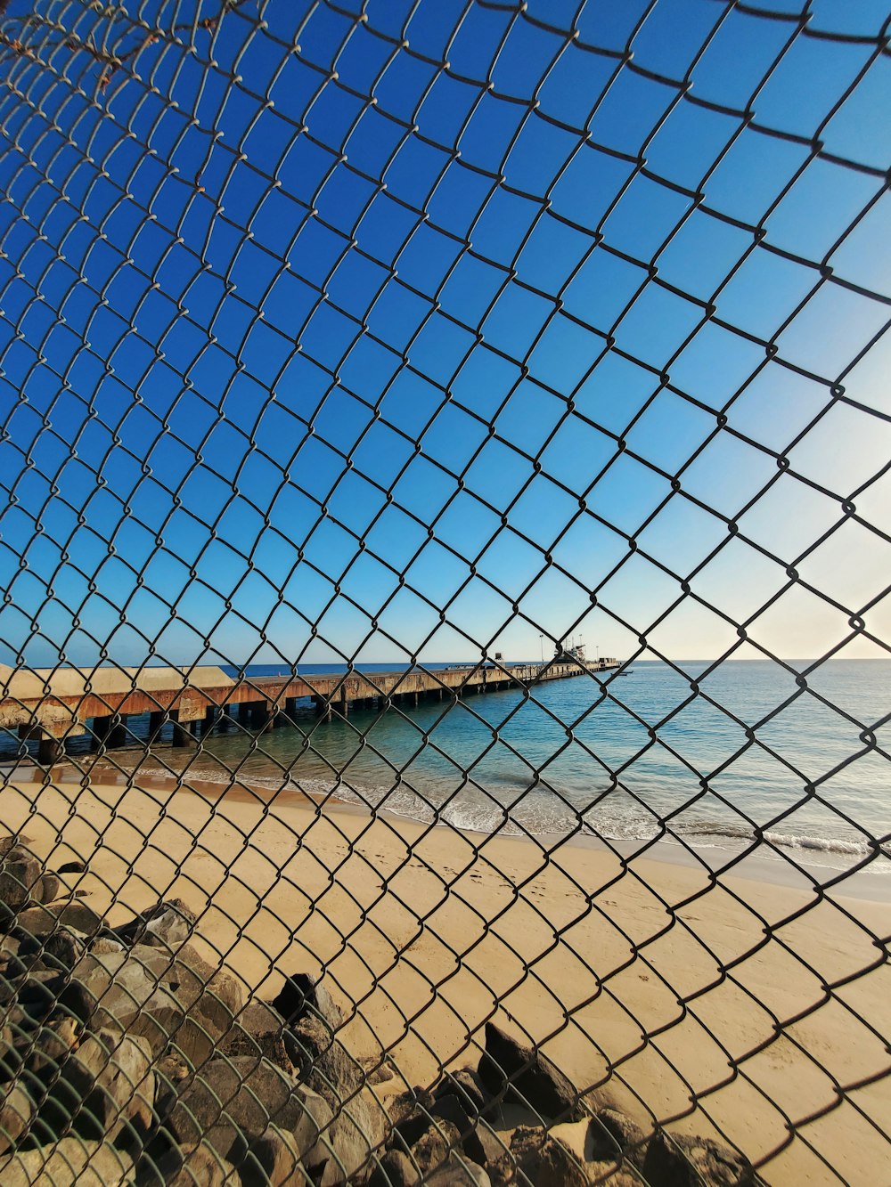 gray metal chain link fence near body of water during daytime