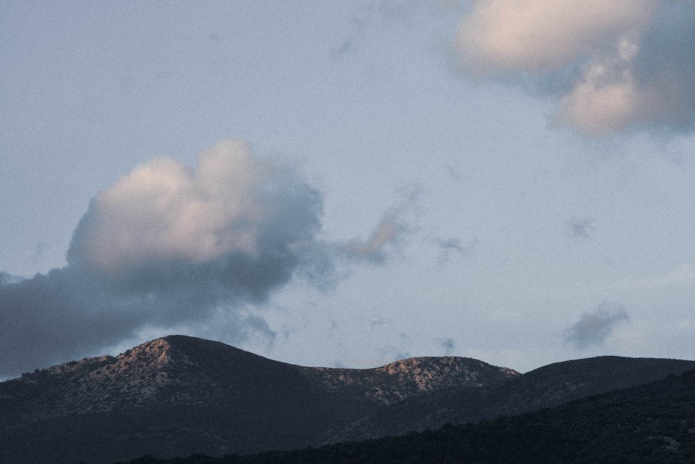 Weiße Wolken über grünem Berg