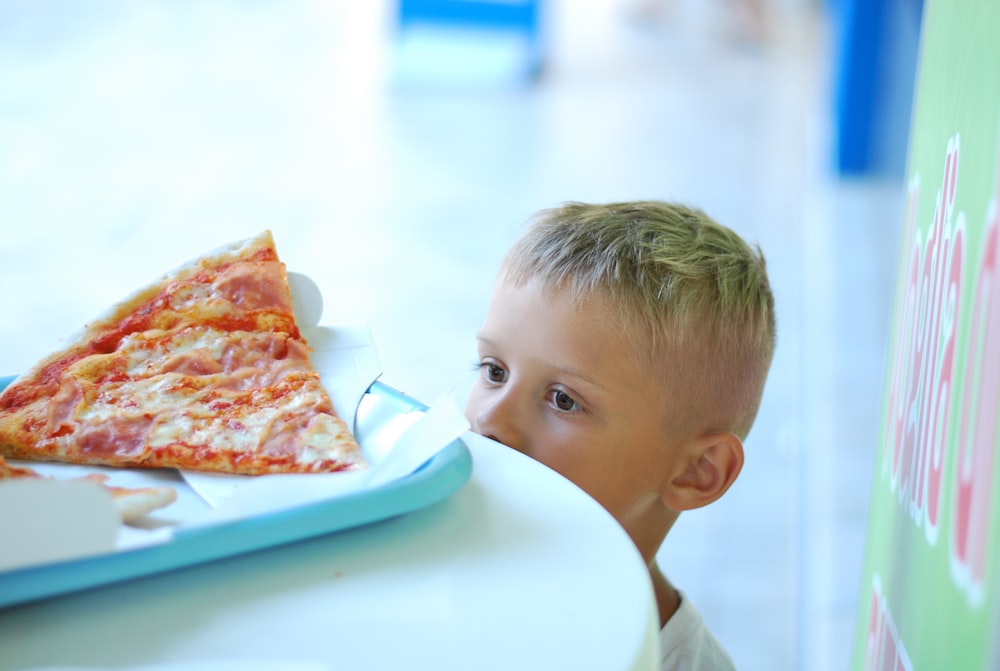 baby in white shirt eating pizza