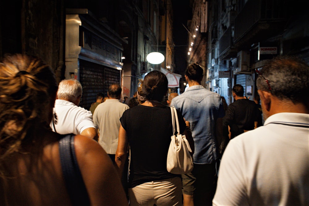 man in black tank top and woman in white shirt walking on street during nighttime