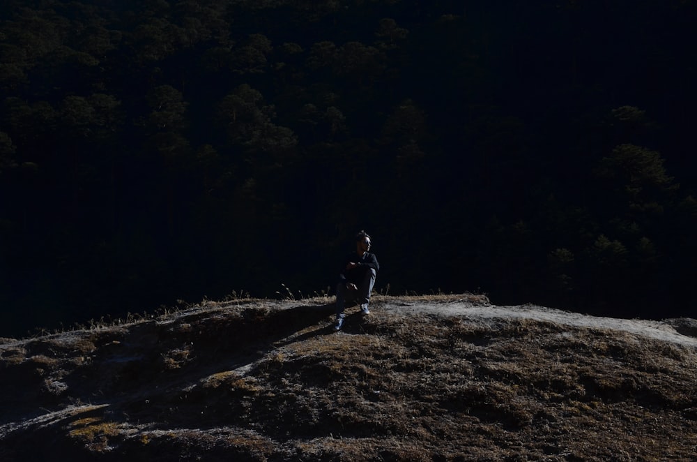 man in black jacket and pants standing on rocky hill during daytime