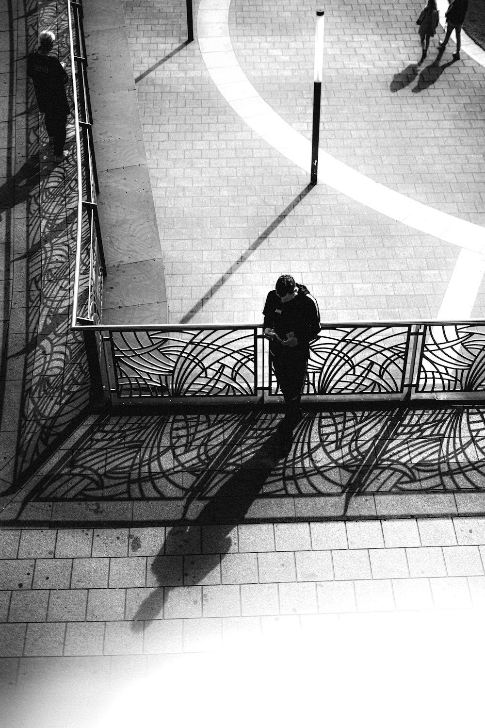 grayscale photo of woman in black jacket and pants standing on sidewalk