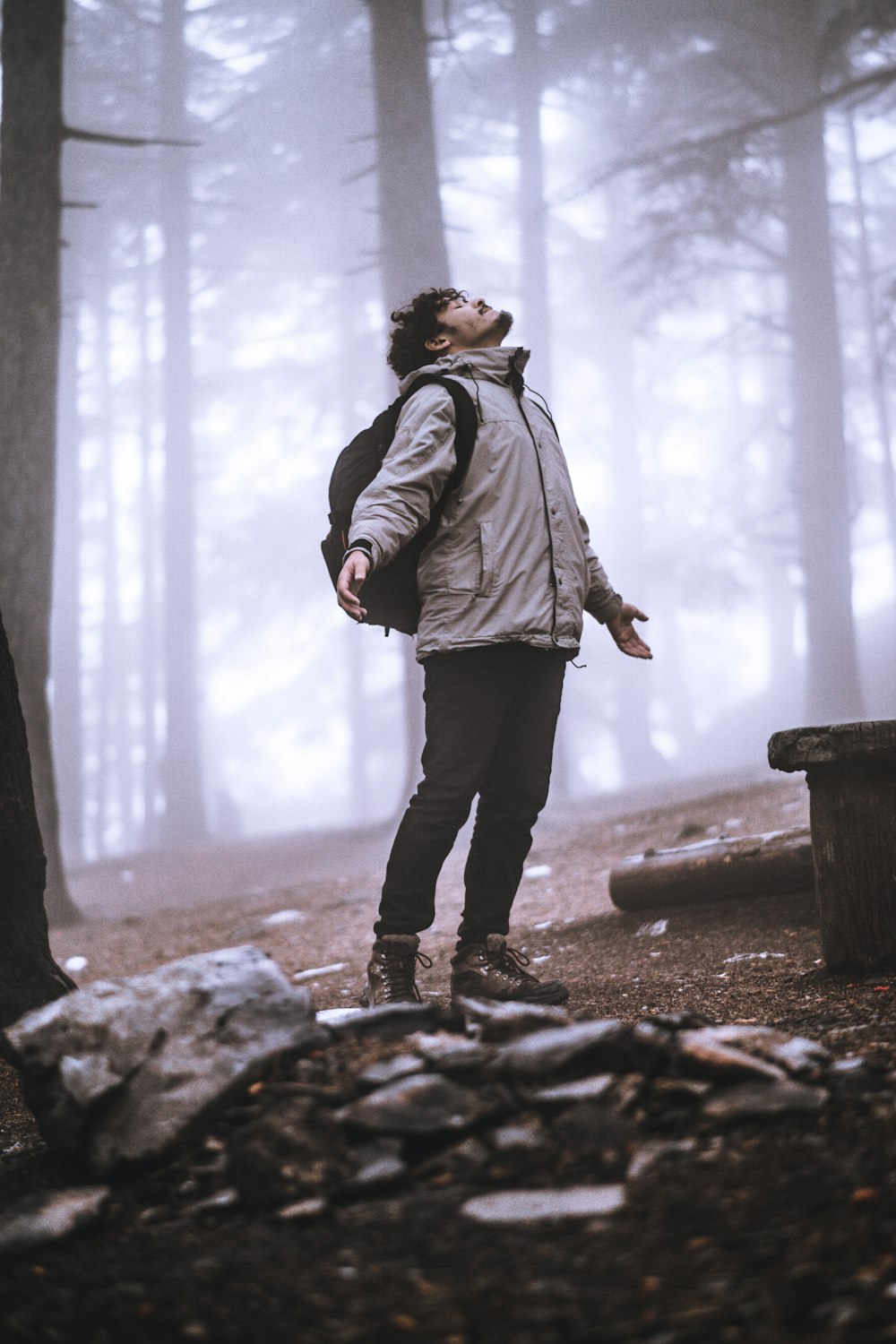 man in gray jacket standing on brown rock during daytime