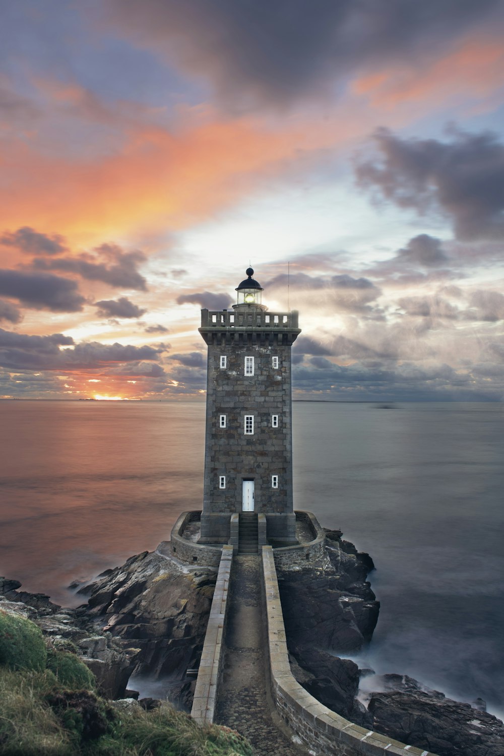 white concrete lighthouse near body of water during sunset