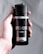 A hand holds a black canister of AXE deodorant and body spray with 'Fresher for Longer' and '48H Fresh' labels. The can is sleek and minimalist in design, featuring bold, white text.