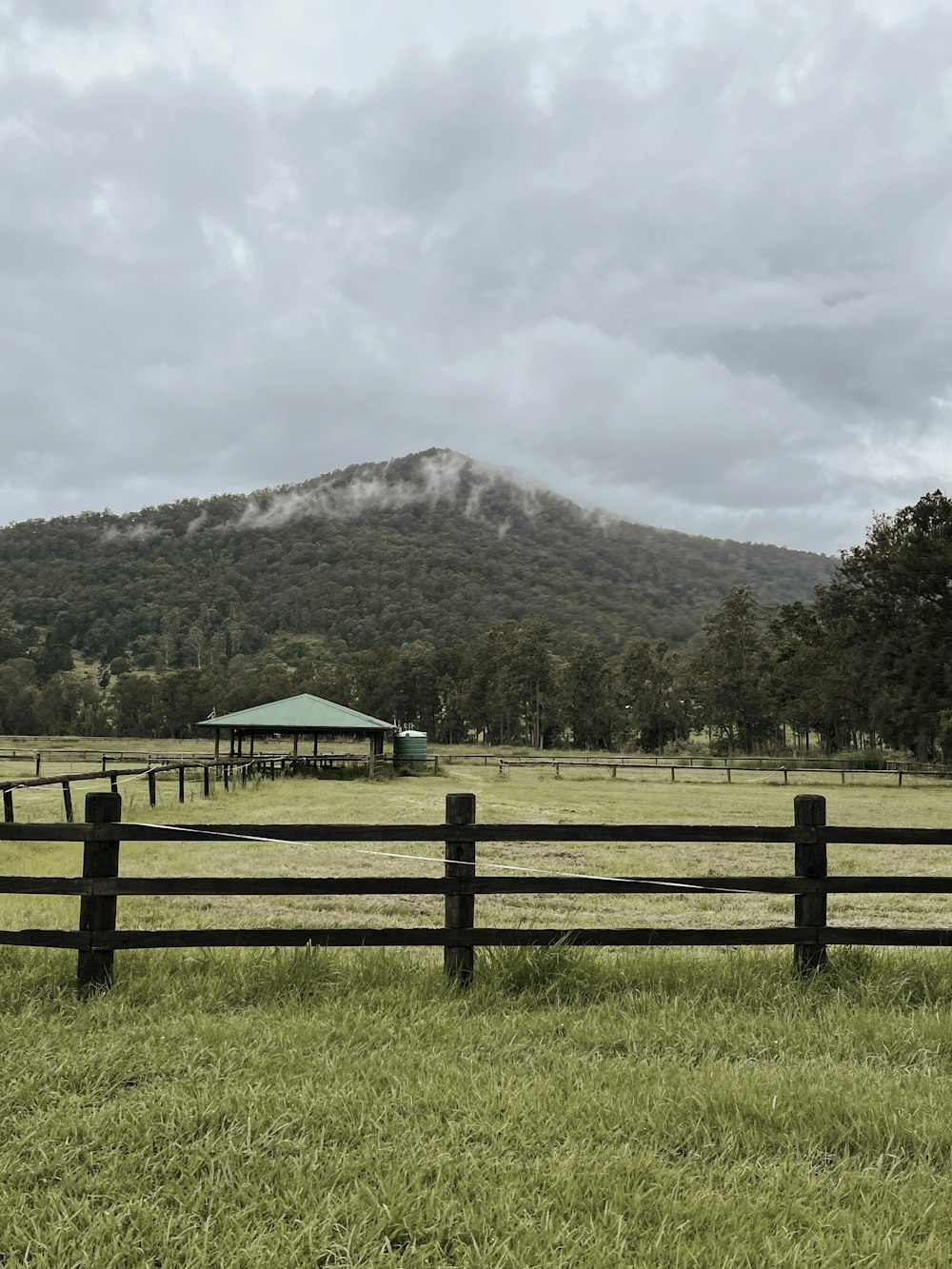 brown wooden fence near green mountain under white clouds during daytime